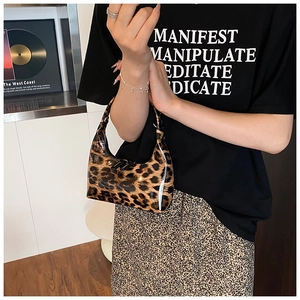 Detail of glossy patent leather leopard print handbag with zipper closure and handle