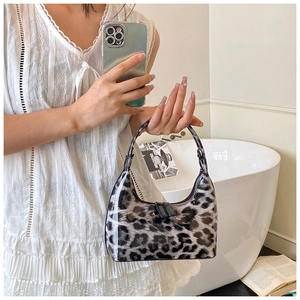 Detail of glossy leopard print hobo bag showing texture and leather shoulder strap