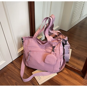 Detail of dusty pink nylon tote bag with multiple zippers and round coin purse accessory
