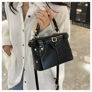 Detailed view of black structured crossbody bag with gold hardware and stitch details