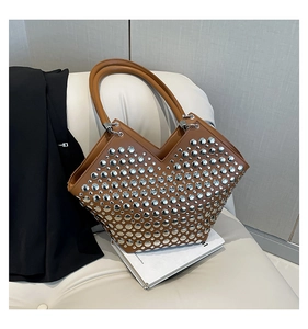 Détails des rivets argentés et de l'ouverture en V sur un sac cabas en cuir couleur caramel