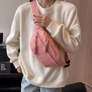 Roze nylon crossbodytas gedragen door model met verstelbare riem en dubbele ritszakken