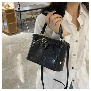 Close-up of black glossy mini box bag with creative denim pocket design and metal studs