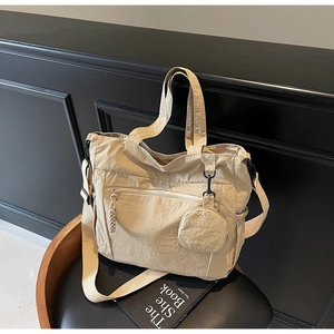 Detailed macro view of beige nylon tote bag with zipper pocket and mini coin purse accessory