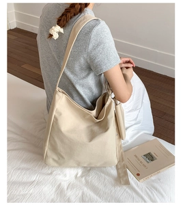 Detailed view of beige canvas tote bag showing soft texture and wide shoulder strap