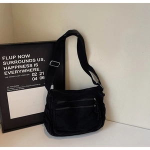 Detailed macro view of black canvas crossbody bag featuring multi-pocket zipper design