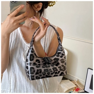Detail of leopard print glossy patent leather handbag with dual zipper closure and black trim