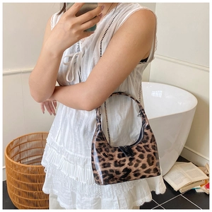 Detail of glossy leopard print handbag with zipper closure and metallic chain strap