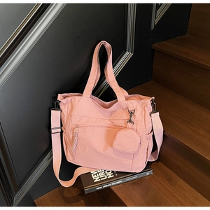 Detail of pink nylon tote bag showing wrinkled texture, zipper pocket and round pouch
