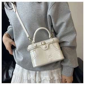 Detailed view of off-white retro box handbag with embossed leather and round handle