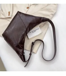 Detail view of dark brown dumpling bag with glossy retro texture and adjustable strap