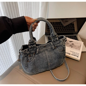 Dettaglio della borsa tote in denim blu con cuciture vintage e rivetti metallici da ufficio