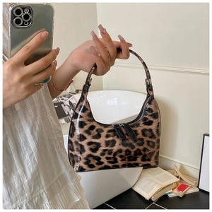 Close-up of the leopard print patent leather crescent bag with dual black zippers and handle