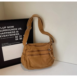 Detail of vintage canvas crossbody bag with multiple front zipper pockets and wide strap