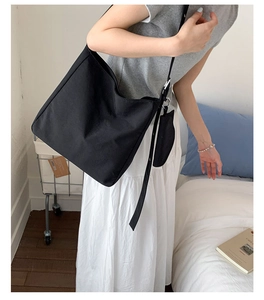 Detail view of large black canvas tote bag with adjustable strap and small pouch