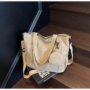 Detail of beige nylon tote bag with mini coin purse on wooden stairs showing texture