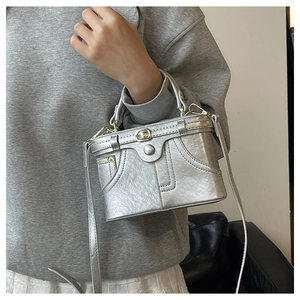 Detail of silver metallic box bag with jacket style stitching and golden buckles