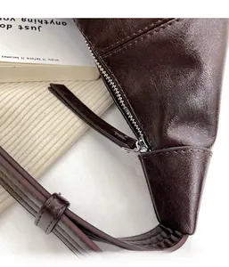 Detail of silver metal zipper and brown litchi pattern leather on a fashion crossbody bag