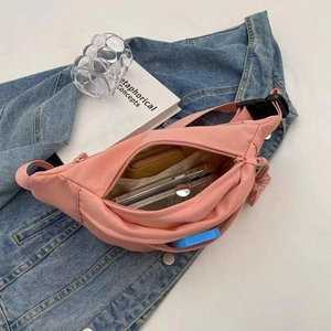 Roze nylon crossbody tas voor dames met zicht op de binnenkant op denim achtergrond