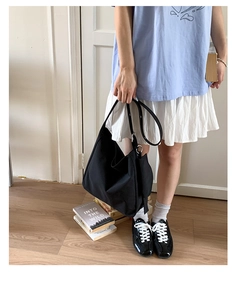 Detail view of the black canvas hobo bag with wide shoulder strap and silver buckle adjustment