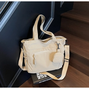Detail of beige nylon tote bag with front zipper pocket and round coin purse on dark wood