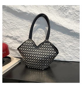 Détail du sac bandoulière en cuir noir avec rivets argentés et découpe en V