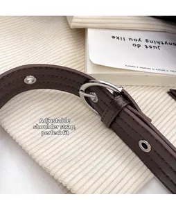 Detail of adjustable dark brown leather shoulder strap with silver buckle and metal eyelets