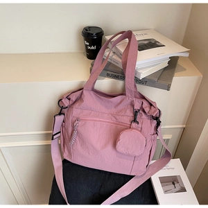 Detail of dusty pink nylon tote bag with wide strap and round coin purse in a workspace