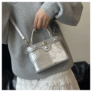 Detail view of the silver denim-style mini bag with industrial metal studs and rivets