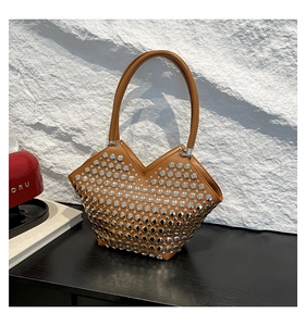 Détail du sac en cuir marron avec rivets argentés et ouverture unique en forme de V