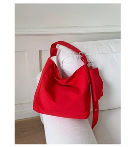Detail of red nylon hobo bag with wide shoulder strap and matching mini coin purse pouch