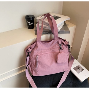 Detail of mauve nylon tote bag featuring a front zipper and matching mini coin purse charm