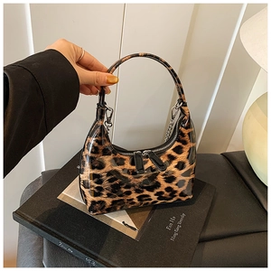 Macro detail of glossy leopard print patent leather handbag with silver chain strap
