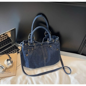 Dettaglio della borsa tote in denim blu con cuciture vintage e rivetti vicino a un laptop