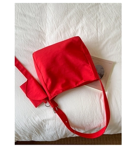 Detail of red canvas tote bag with adjustable wide strap and matching small pouch