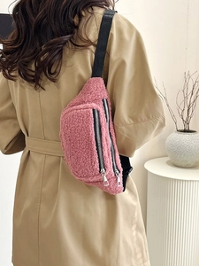 Pink teddy fleece crossbody belt bag with adjustable strap worn over a khaki trench coat