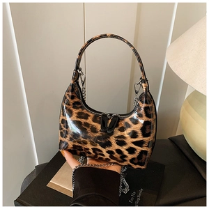Detail of glossy leopard print handbag with silver chain strap on vintage books