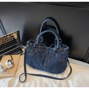 Dettaglio borsa vintage in denim blu con tasche stile giacca e cuciture arancioni a vista