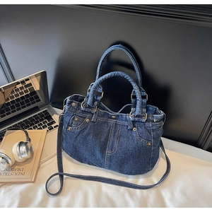 Dettaglio della borsa tote in denim blu con cuciture vintage e rivetti in metallo