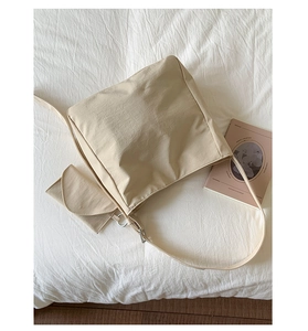 Detail of a beige canvas tote bag with a matching mini pouch on white textured fabric
