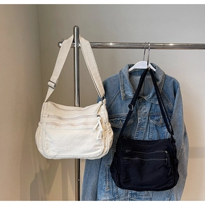 Detail view of multi-pocket canvas crossbody bags in beige and black colors