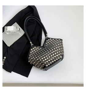 Vue détaillée des rivets ronds argentés sur un sac à main noir en cuir aux accents métalliques