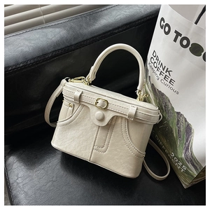 Detail of off-white retro box bag with gold metal lock and faux leather texture