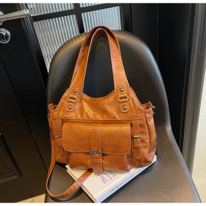 Detail view of a vintage brown lychee grain leather tote bag on a modern chair