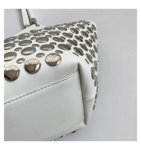 Gros plan des clous en métal argenté et texture fine sur un sac à main blanc en cuir