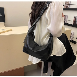 Detail of black leather hobo bag with adjustable wide strap and silver grommets