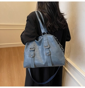 Close-up of blue textured leather tote bag with metallic buckle detail and dual straps
