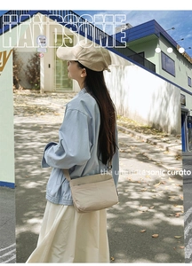 Détail du sac bandoulière en nylon beige avec sangle réglable dans une scène de rue décontractée