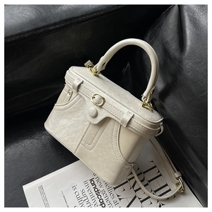 Detailed close-up of cream retro box bag featuring gold lock and leather texture