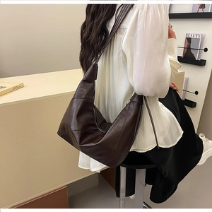 Detail of dark brown PU leather hobo bag with diagonal stitching on a model's shoulder
